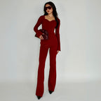 Woman wearing a red knit lounge top holding a clutch against a white background