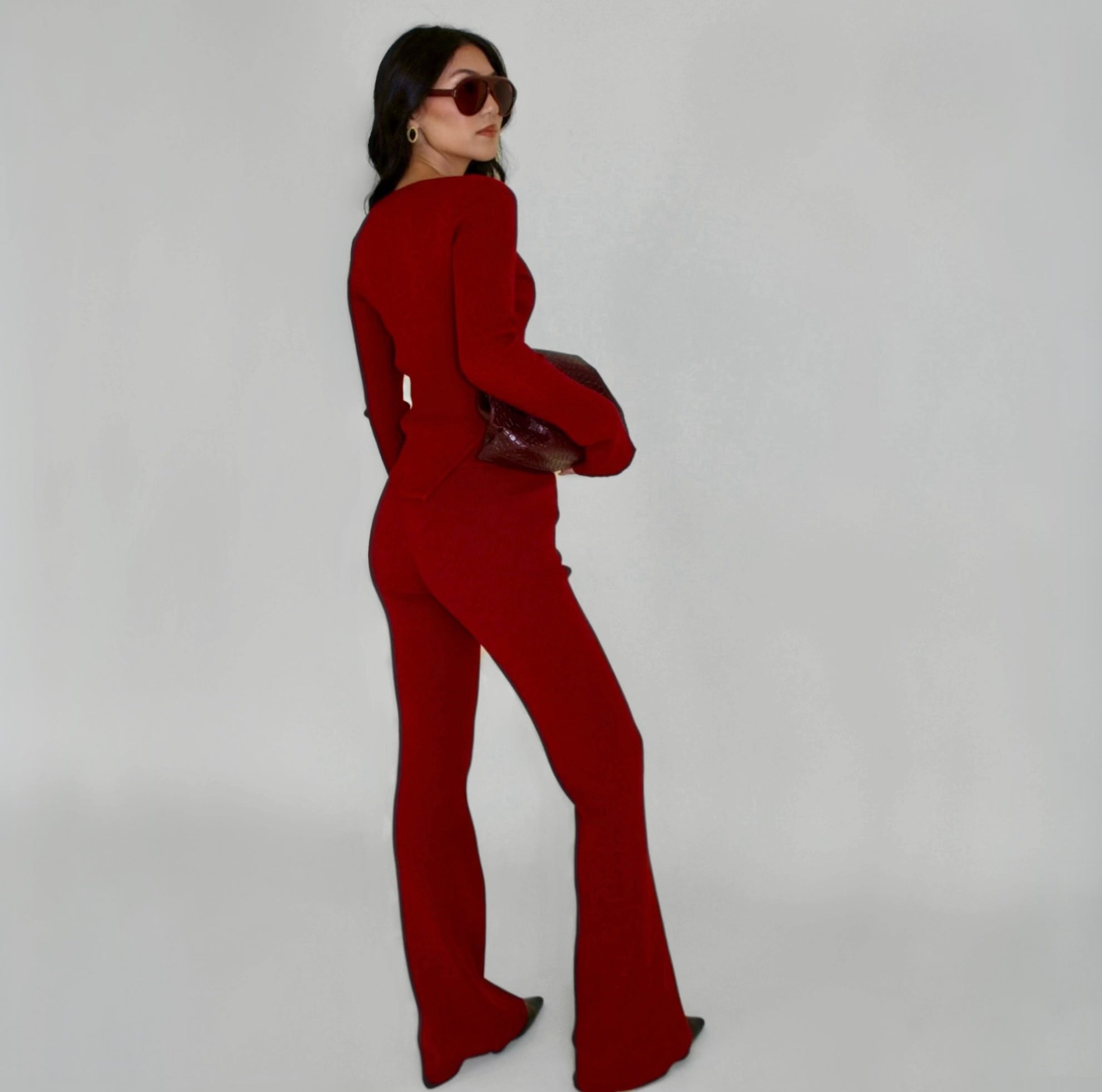 Woman wearing a red loungewear set with flared pants on a plain background