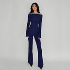 Woman wearing a navy blue off-shoulder jumpsuit on a gray background