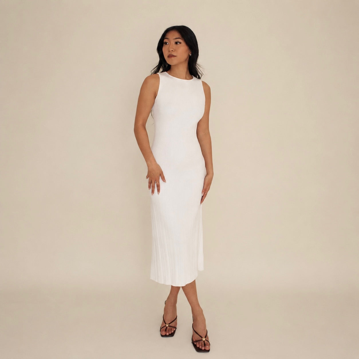 Woman wearing a white lounge sleeveless dress against a beige background